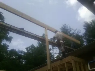 Carpenter setting a ridge beam over a new addition frame — Ice Dam Removal by Roofing Brothers in Oxbow