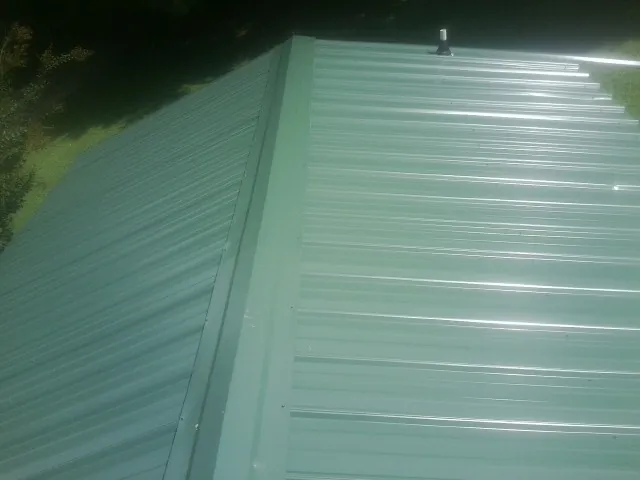 New green metal panels meeting at the ridge of a roof — Flat Roof Repair work by our crew in Oxbow
