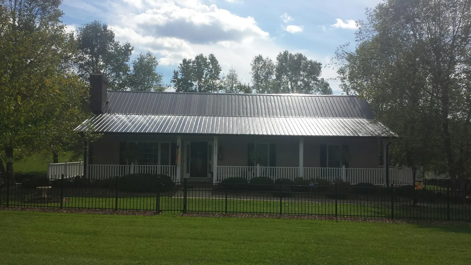 Gray metal roof on a brick ranch with a full width front porch — Gutter Guard Installation work by our crew in Oxbow