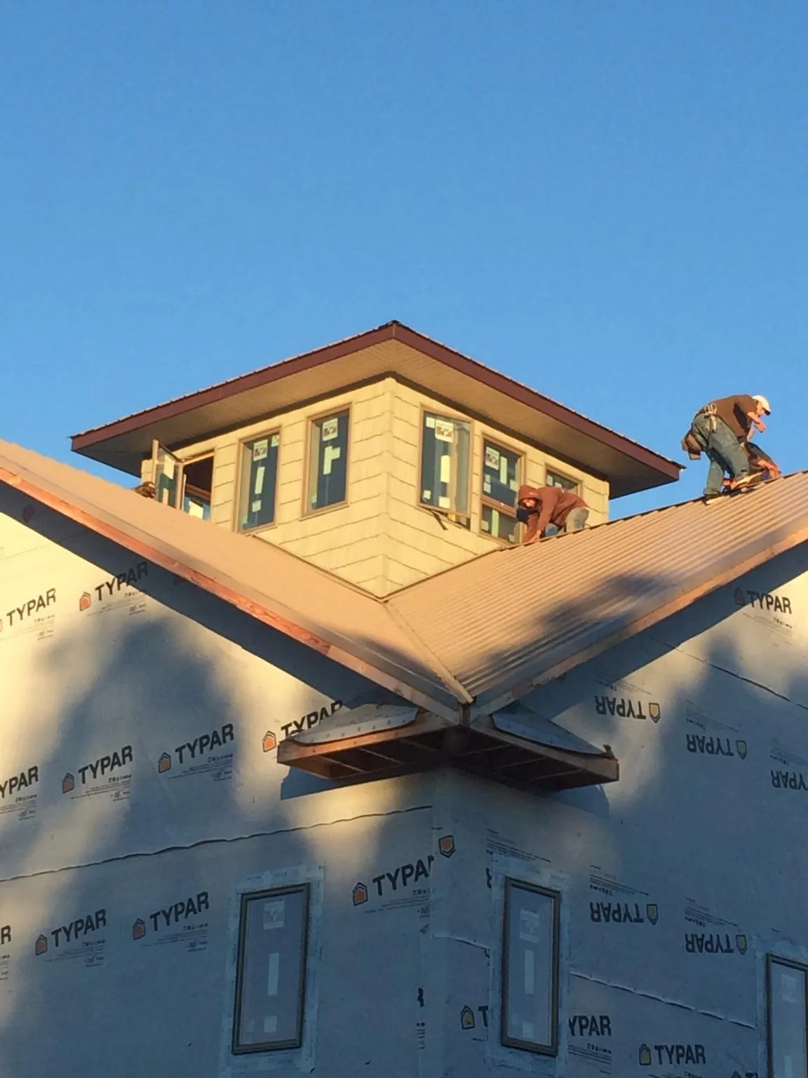 Roofers working around a rooftop cupola on a new metal roof at sunset — Roof Waterproofing in Oxbow by Roofing Brothers